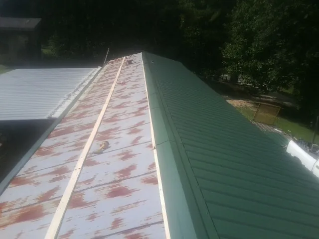 Old rusted panels beside newly installed green metal roofing — Wind Damage Roof Repair by Roofing Brothers in La Mirada