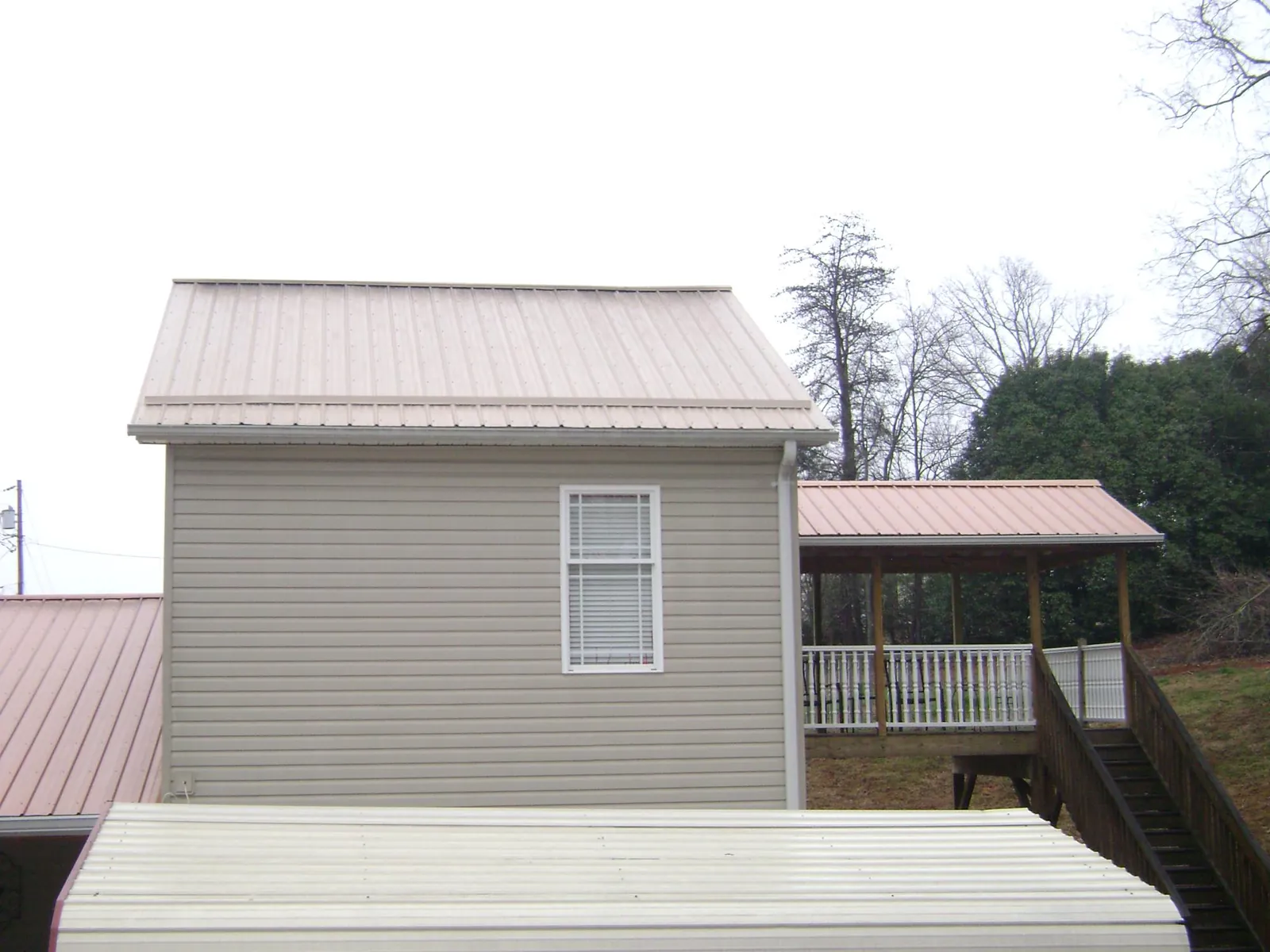 Tan metal roofs on a two story addition and attached porch, from a Roof Replacement job in La Mirada